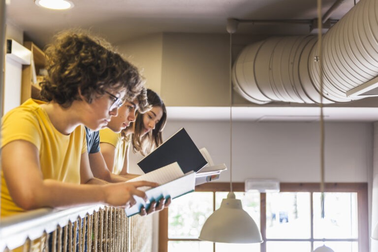 amigos-adolescentes-leyendo-cerca-de-barandilla